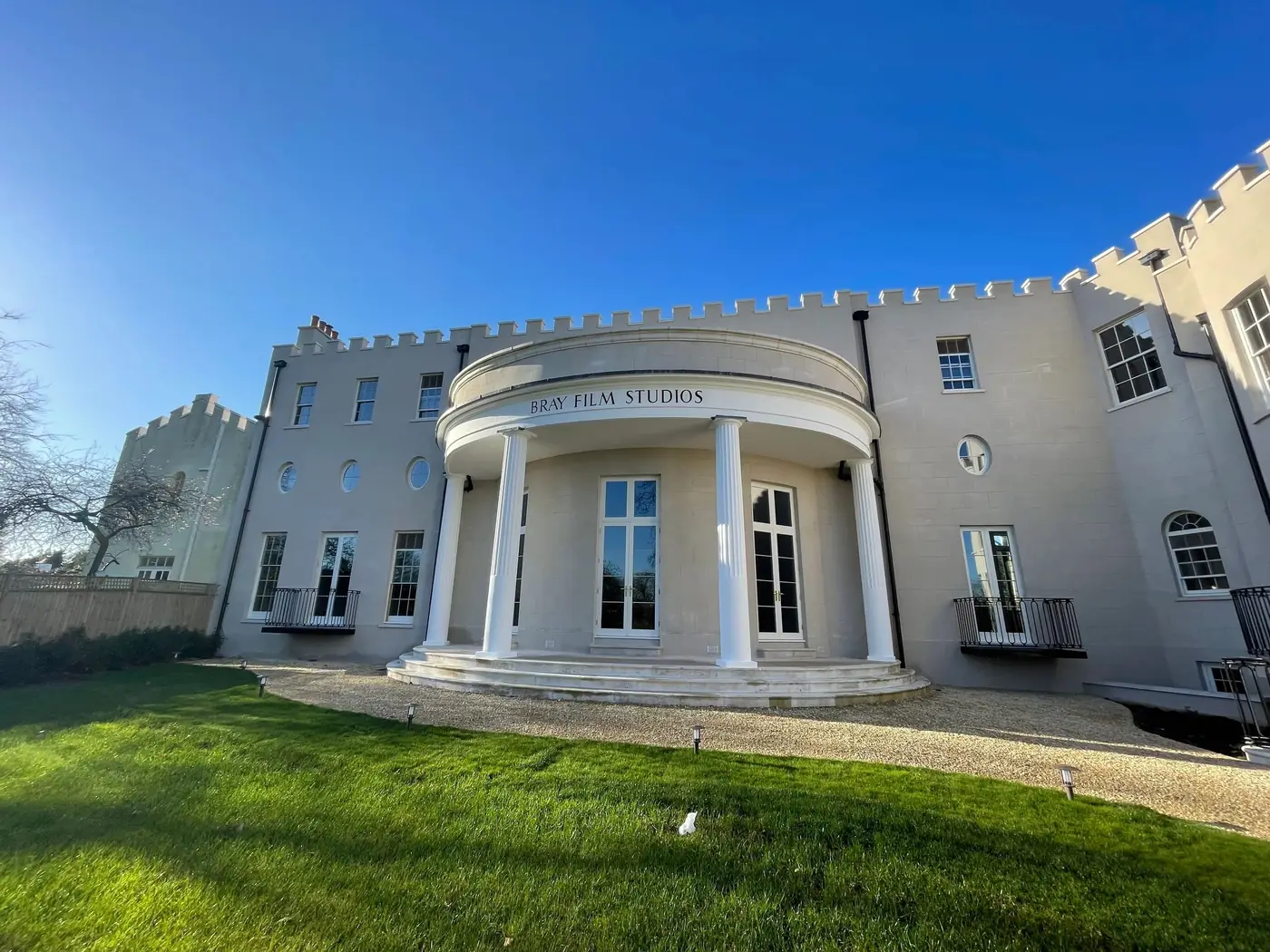 A white country house with a columned portico, finished and landscaped