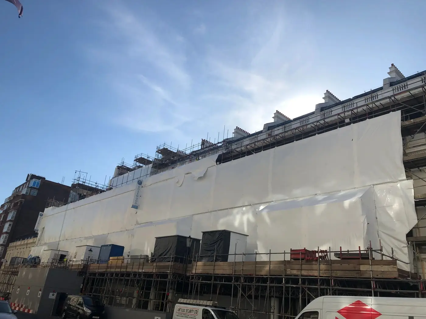 A London facade wrapped for refurbishment under a blue sky